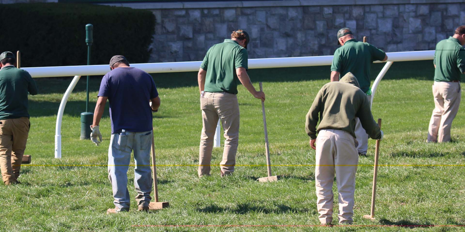 An action shot of Keenland team members tamping down turf divots.